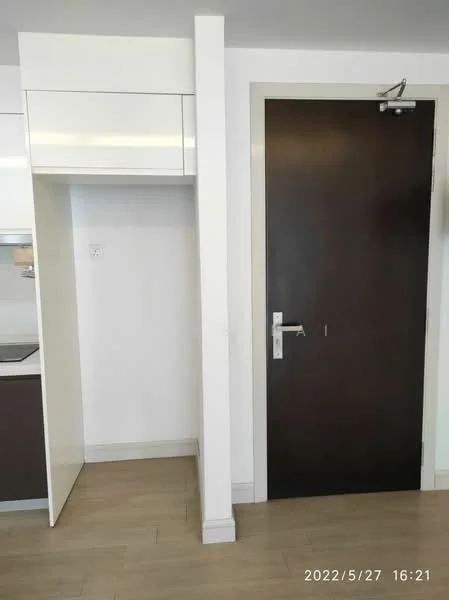 Room features: white cabinetry, dark wood door, light wood flooring, wall-mounted light switch, neutral wall color, modern door handle, kitchenette area, open space layout; style: modern.
