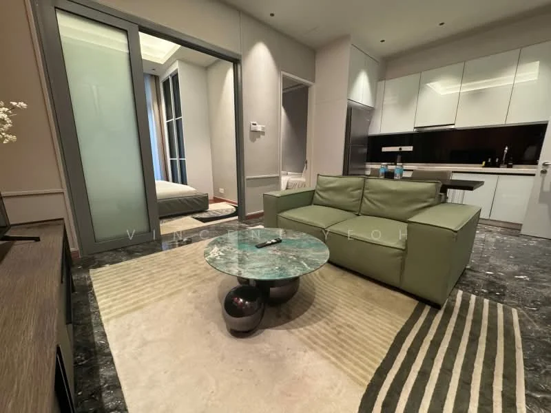 Living features: green fabric sofa, glass coffee table with marble top, area rug with geometric pattern, wall-mounted TV, TV console, recessed downlights, sliding glass door, grey marble flooring, white painted walls, open kitchen area, kitchen cabinetry with glossy finish, kitchen countertop with dark surface; style: modern.