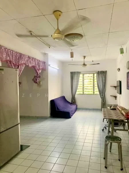 Living features: white painted walls, ceiling with tiles, floor tiles in light color, 2 ceiling fans, window with sheer curtains, sofa covered with purple fabric, small wall-mounted shelf, dining table with stools, refrigerator, open layout.