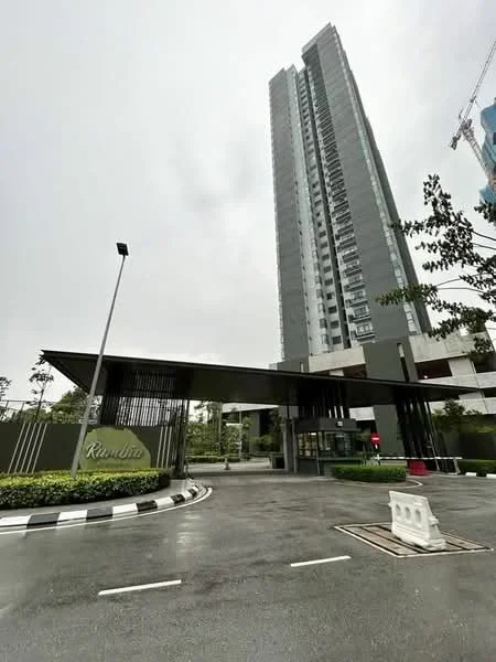 Exterior type: high-rise condominium; features: glass curtain wall, green accent facade, recessed balconies, landscaped entrance, manicured lawn, paved driveway, security guard house at entrance, CCTV cameras visible, gated entry, surrounded by greenery; style: modern.
