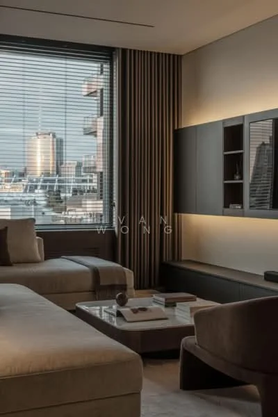 Living features: large sectional sofa in beige fabric, coffee table with marble top, TV console with built-in shelving, floor-to-ceiling windows with city view, sheer curtains, recessed LED lighting, decorative wall paneling, neutral wall color, area rug with geometric pattern, accent chair in dark fabric; style: modern; view: city.