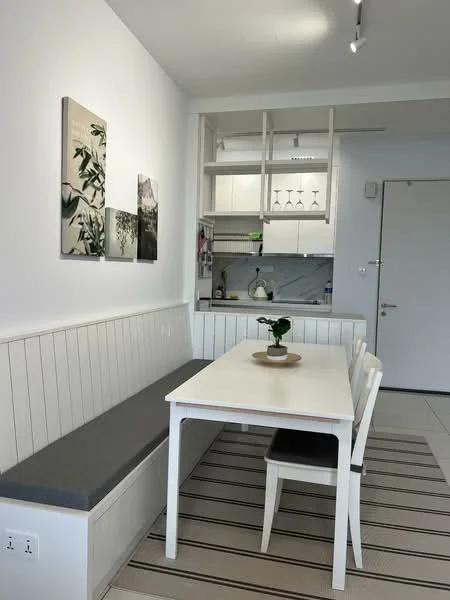 Dining features: white dining table, 4 white dining chairs, grey upholstered bench seating, white cabinetry with glass shelves, marble backsplash, white painted walls, striped area rug, recessed lighting, wall art with botanical prints, open shelving, kitchen sink visible, kitchen utensils visible; style: modern.