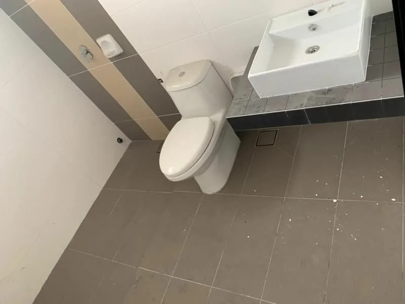 Bathroom features: white ceramic toilet, white sink, grey tile flooring, white tiled walls, beige accent wall, chrome faucet, square sink design, floor drain, wall-mounted toilet paper holder; style: modern.