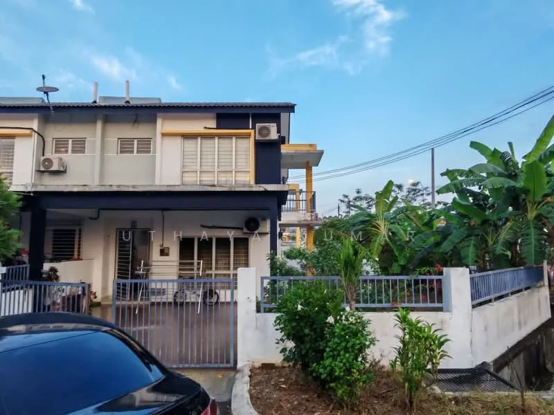 Exterior type: linked terrace house; features: two-storey building, grey and black painted facade, balcony on the upper floor, manicured garden with shrubs, paved walkway, fence surrounding the property, visible air conditioning units, car parked in front, banana trees in the garden, clear blue sky; style: modern.