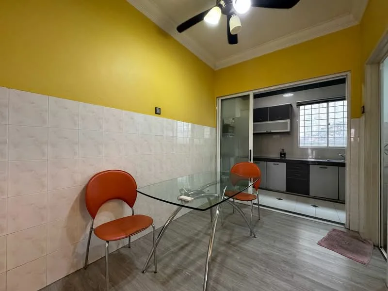 Dining features: yellow painted walls, white tiled walls, glass dining table, 2 orange chairs, laminate flooring, ceiling fan with light, window with grid pattern, doorway leading to kitchen; style: modern. Kitchen features: white cabinetry, black countertops, stainless-steel appliances, tile flooring, window with grid pattern; style: modern.