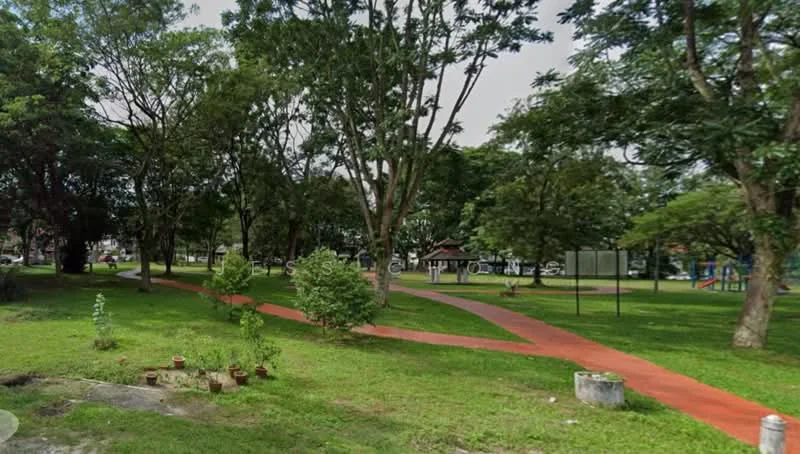 Exterior type: landscape garden; features: manicured lawn, mature trees, walking path with red paving, flower pots, playground equipment visible in background, open green space; style: tropical-modern.
