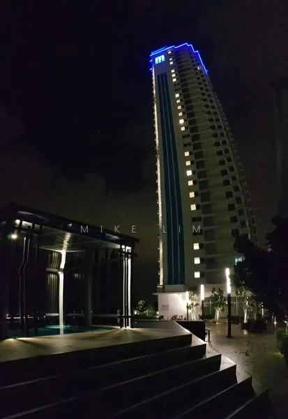 Exterior type: high-rise condominium; features: illuminated building facade, blue accent lighting, glass curtain wall, multiple storeys, surrounding landscaping, pool deck area, outdoor lighting, modern architectural design; style: modern.
