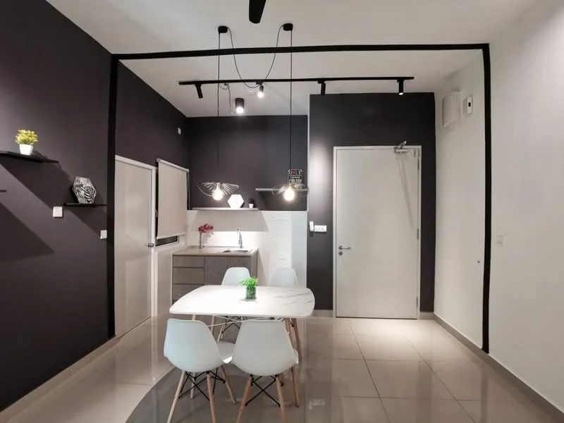 Dining features: white dining table with wooden legs, 4 white chairs with wooden legs, dark grey accent wall, white walls, recessed downlights, pendant lighting above the table, kitchenette with grey cabinetry, stainless-steel sink, countertop with grey finish, open shelving on the wall, decorative plant on the table; style: modern.