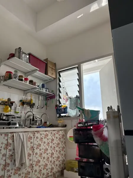Kitchen features: white painted walls, flat ceiling, open shelving, stainless-steel sink, chrome pull-down faucet, floral-patterned cabinetry, window with louvered design, various kitchen utensils and containers, laundry hanging outside the window, plastic storage bins, dish rack, countertop with appliances; style: modern.