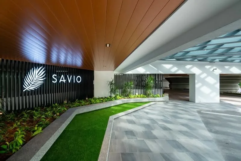 Exterior features: decorative signage with logo, landscaped area with greenery, stone-paved walkway, modern ceiling design, indirect lighting, horizontal slatted fencing, planters with plants, grey tiled flooring; style: modern.