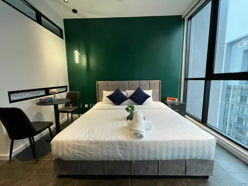 Bedroom features: king-size bed with upholstered headboard, white bedding with decorative pillows, green accent wall, floor-to-ceiling windows, grey bedside table, black chair, small round table, decorative plant on table, recessed ceiling lights, tile flooring; style: modern; view: city.