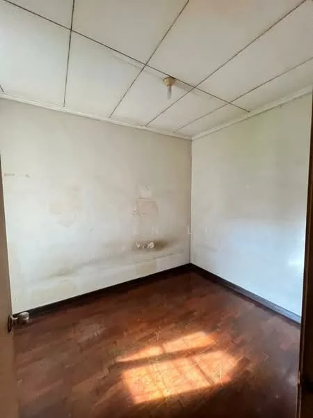 Room features: plain white walls, wooden flooring, ceiling light fixture, no visible furniture, natural light from window, corner with wall damage, unpainted ceiling tiles, single door entrance.