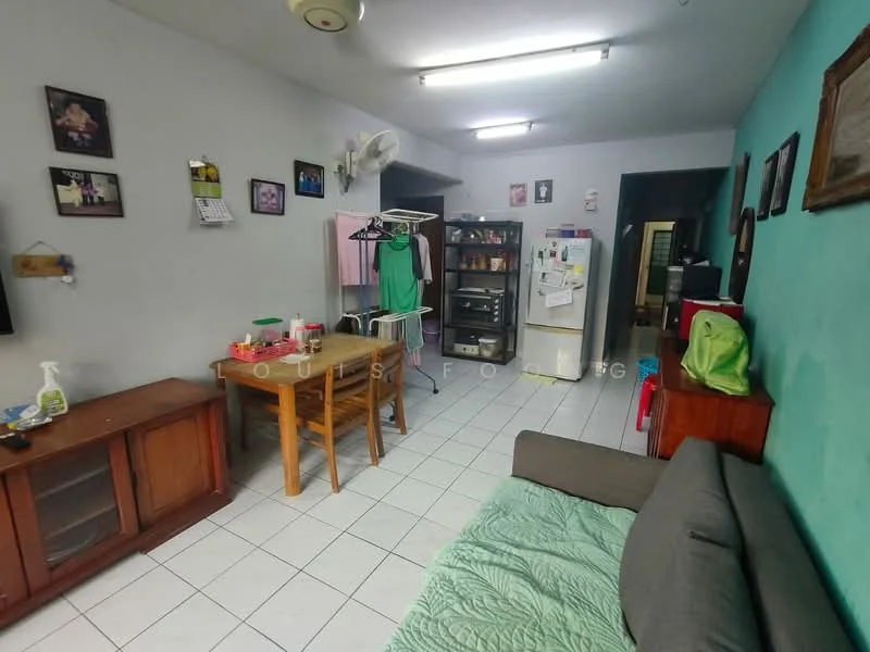 Living features: grey fabric sofa, wooden coffee table, TV console, wall-mounted TV, white tiled flooring, ceiling fan, wall-mounted air conditioning unit, framed artwork on walls, green accent wall, dining table with four chairs, kitchenette area with cabinets, refrigerator, laundry rack.