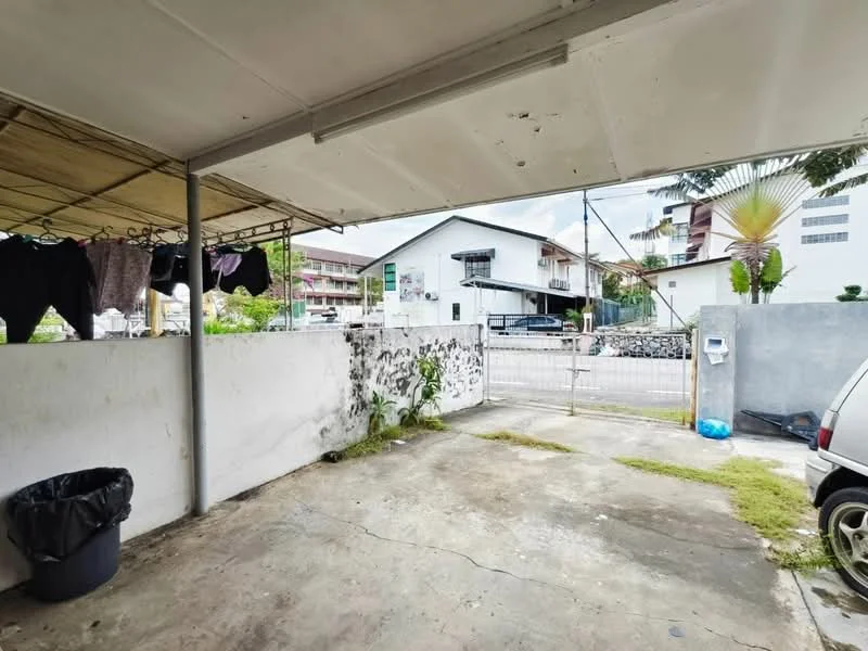 Exterior type: car porch; features: concrete flooring, covered roof, clothesline with hanging clothes, fenced perimeter, gate at entrance, adjacent residential building, manicured grass patch, garbage bin; style: modern.