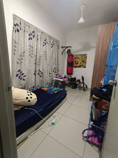 Bedroom features: single bed with blue bedding, white painted walls, floor-to-ceiling window with floral curtains, ceiling fan, tiled flooring, wooden wardrobe with vertical stripes, punching bag, guitar, clothes rack, decorative poster on wall, various personal items on floor.