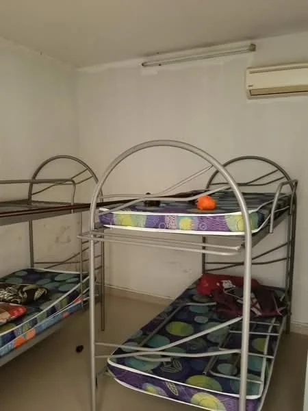 Room features: bunk beds with metal frame, mattresses with colorful patterned covers, air conditioning unit on wall, plain white walls, light-colored flooring, minimal decor; style: minimalist.