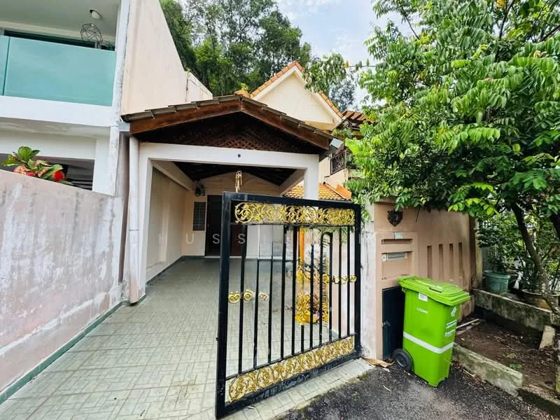 Exterior type: detached bungalow; features: gated entrance with decorative metal gate, covered car porch, green waste bin, paved driveway, surrounded by greenery, sloped roof, exterior wall with light-colored finish, mature trees, garden area; style: traditional.