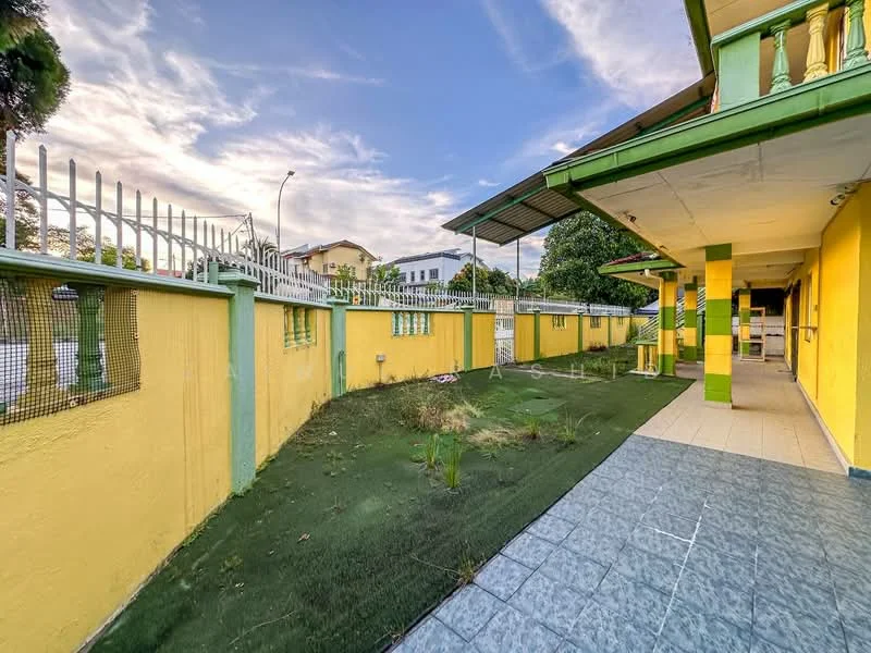 Exterior type: detached bungalow; features: yellow painted facade, green trim, fenced perimeter, manicured lawn, paved walkway, outdoor area with grass, covered porch, single-storey, surrounded by greenery, urban context; style: traditional.