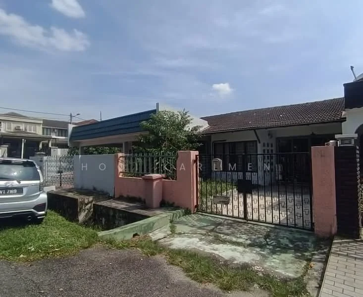 Exterior type: detached bungalow; features: single-storey, pink painted facade, gated entrance with metal gate, manicured lawn, paved driveway, car parked in driveway, roof overhang, exposed brick wall, surrounded by greenery, concrete pathway; style: traditional.