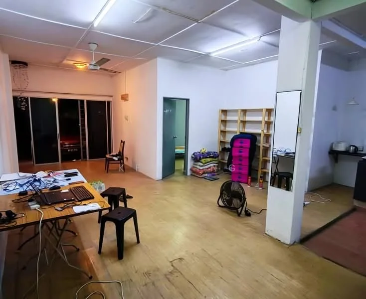 Room features: wooden flooring, white painted walls, ceiling fan, large sliding glass door, open layout, built-in shelving unit, table with laptop, plastic chairs, floor fan, kitchen area visible, mirror on wall, decorative light fixture; style: modern.