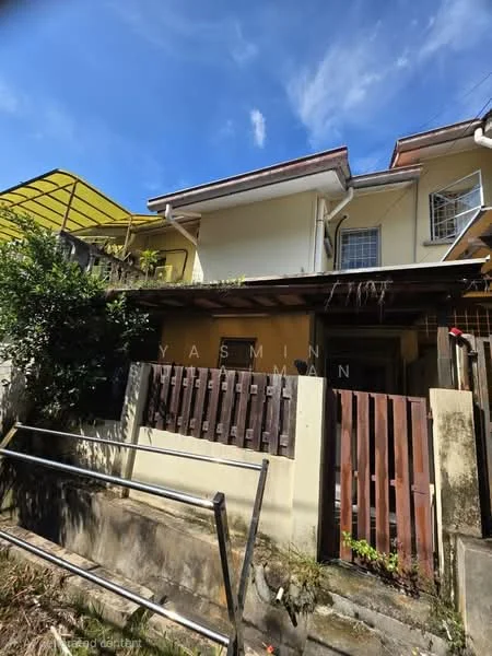 Exterior type: linked terrace house; features: yellow painted facade, wooden front gate, covered porch area, two-storey structure, sloped roof, overhanging eaves, surrounded by greenery, concrete pathway, fenced yard, visible drainage system; style: traditional.
