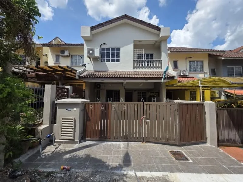 Exterior type: linked terrace house; features: two-storey building, white painted facade, brown wooden gate, paved driveway, manicured garden area, air conditioning unit visible, covered porch, terracotta roof tiles, balcony on upper floor, surrounded by greenery; style: modern.