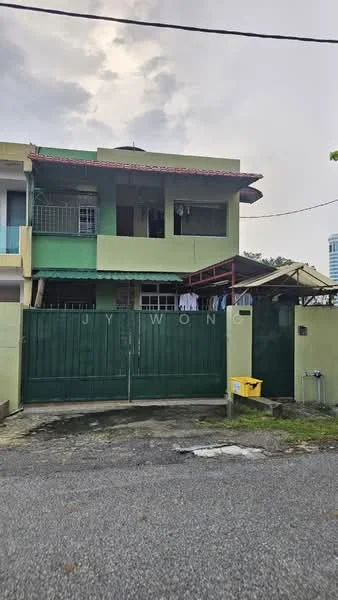 Exterior type: semi-detached house; features: green painted facade, red tiled roof, two-storey structure, metal gate, concrete driveway, balcony on upper floor, windows with metal grilles, covered porch area, surrounded by greenery; style: traditional.