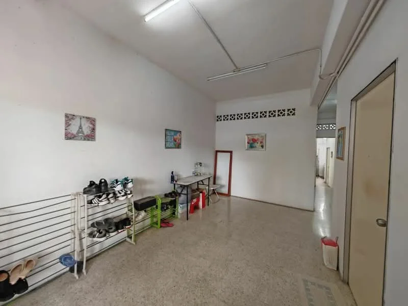 Room features: white painted walls, polished concrete flooring, fluorescent ceiling lights, shoe rack, green folding chair, decorative wall art, doorway leading to other rooms, open space layout; style: minimalist.