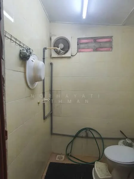 Bathroom features: white painted walls, ceramic tile flooring, one-piece toilet, exhaust fan, window with glass panes, hose for cleaning, hat hanging on hook, towel rack.