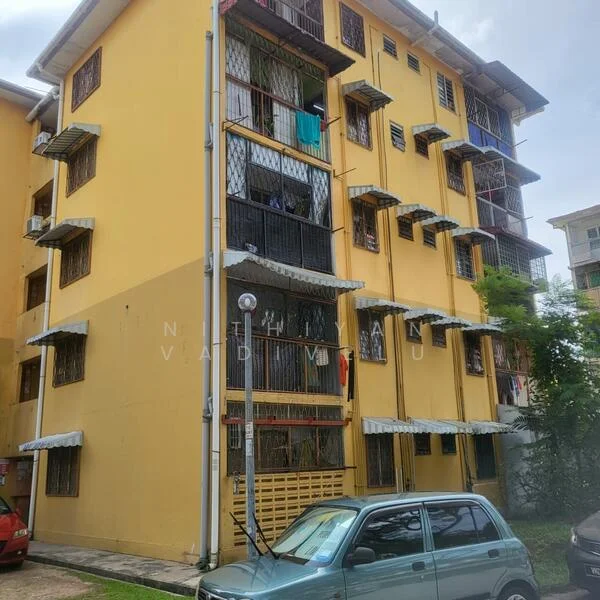 Exterior type: low-rise apartment block; features: yellow painted facade, multiple floors, balconies with metal railings, window grilles, awnings over windows, parking area in front, surrounding greenery; style: modern.
