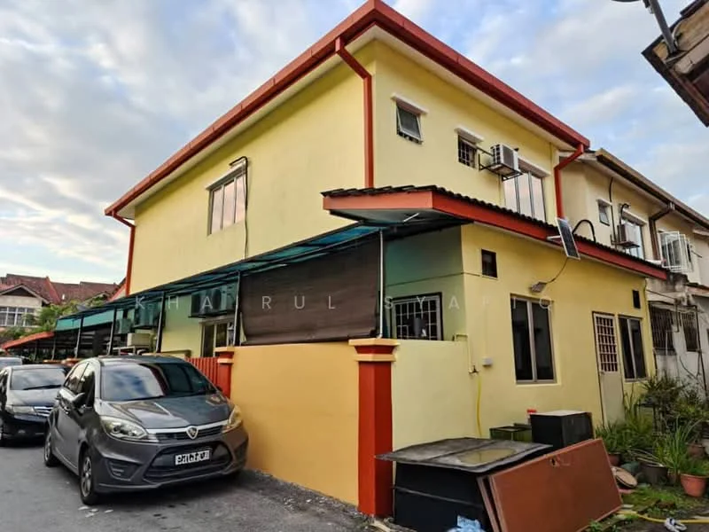 Exterior type: semi-detached house; features: yellow painted facade, red trim around windows and roof, flat roof, two-storey structure, visible car porch, windows with grilles, awnings over windows, manicured landscaping, driveway with interlocking pavers; style: modern.