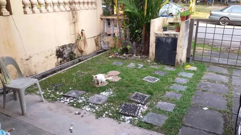 Exterior type: linked terrace house; features: paved walkway with stone slabs, manicured lawn, decorative stones, fenced area, small garden with plants, outdoor seating area with chair, visible drainage, front gate; style: traditional.