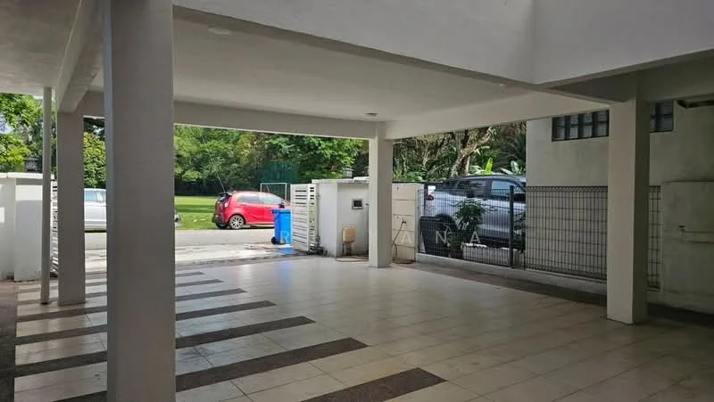 Exterior type: car porch; features: open-air parking area, tiled flooring, white painted walls, columns supporting the roof, manicured lawn visible in background, fenced perimeter, driveway with interlocking pavers, visible car parked, blue trash bin, greenery surrounding the area; style: modern.