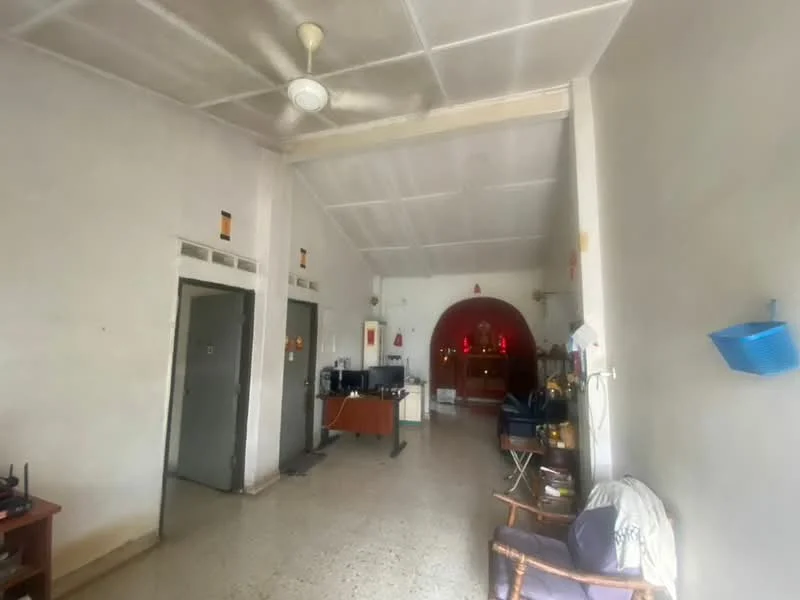 Room features: white painted walls, concrete flooring, high ceiling, ceiling fan, wall-mounted light fixtures, open layout, two doors on the left, arched wall feature at the end, wooden furniture, decorative items on shelves, seating area with chair; style: minimalist.