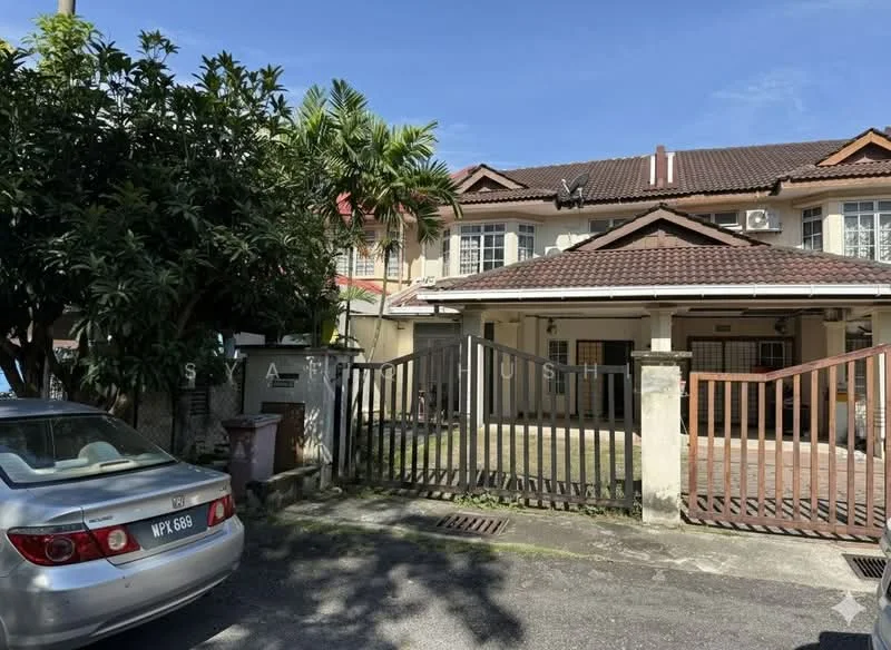 Exterior type: linked terrace house; features: brown tiled roof, cream painted facade, front yard with grass, metal gate, driveway with interlocking pavers, two-storey structure, air conditioning units visible, mature trees in front, fenced perimeter, parking space for one car; style: modern.