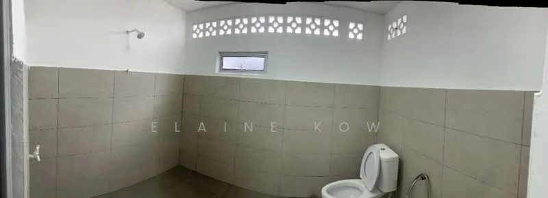 Bathroom features: white toilet, grey ceramic tile flooring, light grey wall tiles, white painted walls, window with decorative grille, showerhead fixture on wall, corner shower area, no visible vanity or sink.