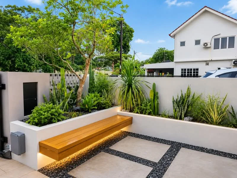 Exterior type: detached bungalow; features: landscaped garden with various plants, wooden bench with integrated lighting, stone-paved walkway, decorative gravel, fenced perimeter, mature trees, low-maintenance plants, exterior wall with modern design, visible car parking area; style: modern.