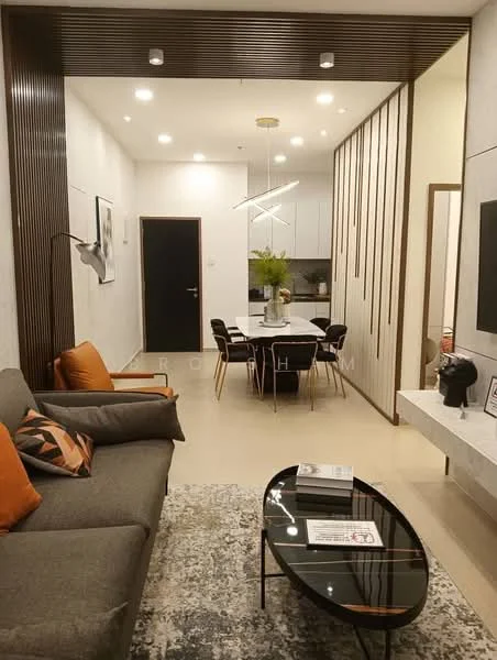 Living features: grey fabric sofa, orange accent cushions, coffee table with glass top, area rug with geometric pattern, wall-mounted TV, feature wall with wooden slats, recessed downlights, pendant light fixture, decorative wall art, dining table with white top and black legs, four dining chairs, open kitchen with white cabinetry; style: modern.