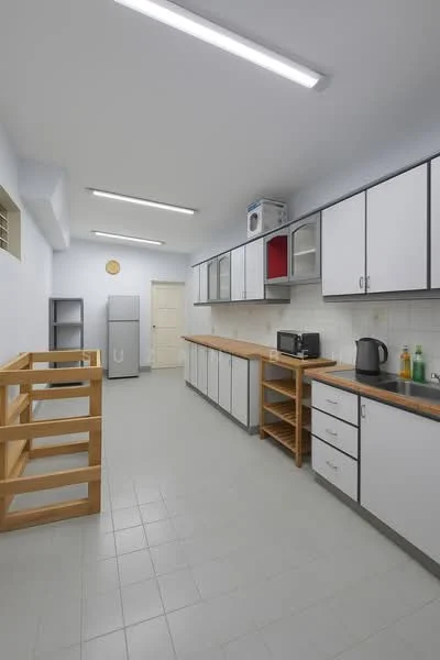 Kitchen features: white cabinetry with grey countertops, stainless-steel fridge, built-in microwave, black kettle, wooden shelving unit, tile flooring, wall-mounted cabinets, sink with faucet, light fixtures on ceiling, door leading to another room; style: modern.