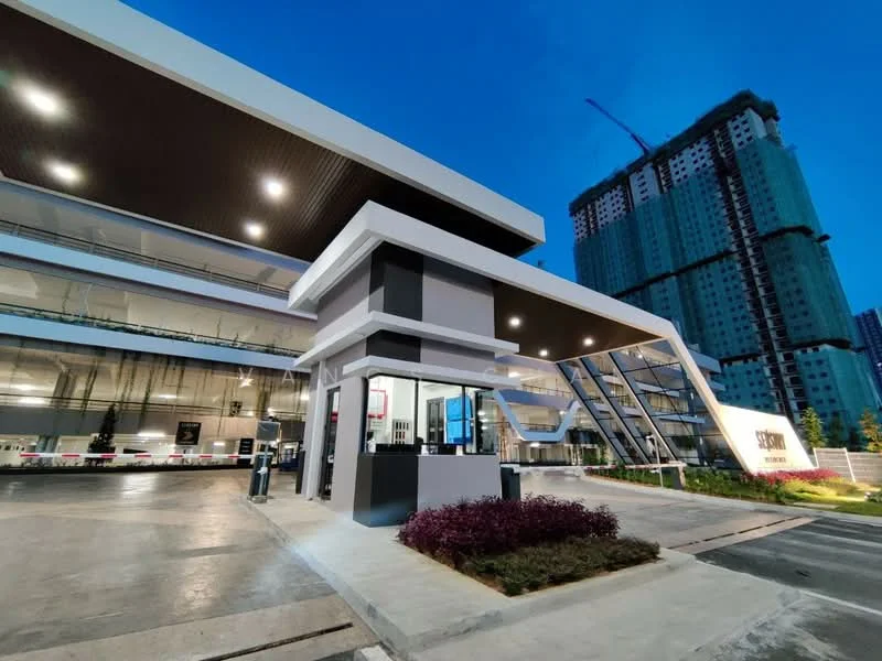 Exterior type: clubhouse; features: modern architectural design, glass facade, flat roof, recessed lighting, landscaped garden with shrubs, paved driveway, security guardhouse, large windows, entrance with awning, surrounding construction site, night lighting; style: modern.
