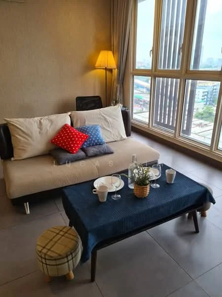 Living features: 3-seater fabric sofa in beige, decorative cushions in red and blue, wooden coffee table, tablecloth in navy blue, decorative plant in pot, 2 cups on the table, lamp with warm light, floor-to-ceiling windows, grey tiled flooring, curtains in light fabric; style: modern; view: city.