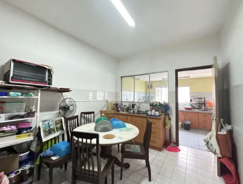 Kitchen features: white painted walls, tile flooring, wood cabinetry, round dining table, 4 wooden dining chairs, ceiling light fixture, wall-mounted fan, kitchen counter with sink, various kitchen appliances, open shelving, multiple pots and pans, colorful kitchen accessories.