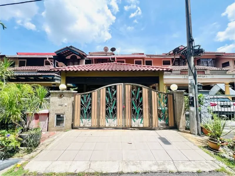 Exterior type: linked terrace house; features: decorative metal gate with floral design, paved driveway, manicured garden with potted plants, red tiled roof, two-storey structure, front porch area, visible satellite dishes, outdoor lighting fixtures, brick facade, surrounding greenery; style: traditional.