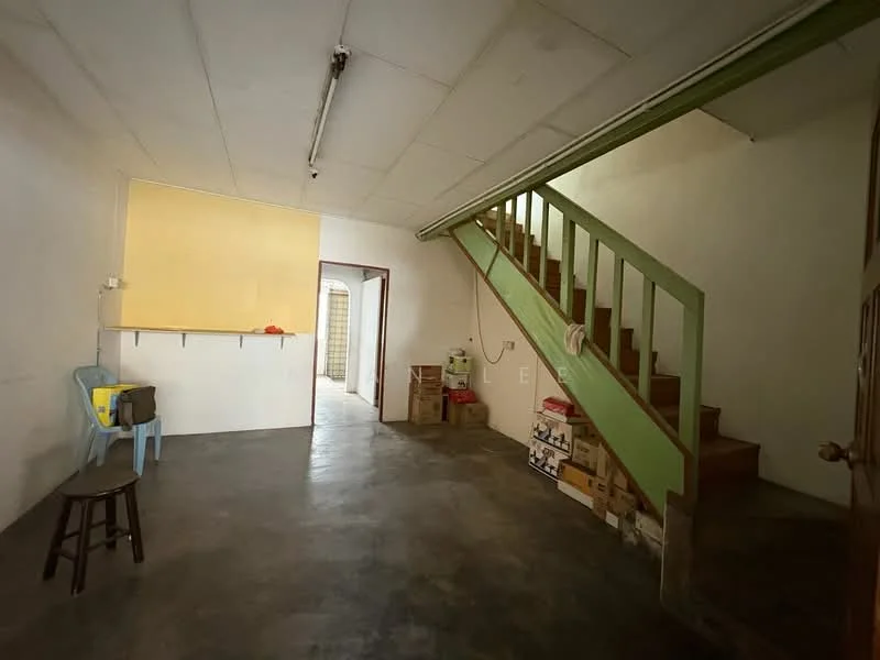 Room features: concrete flooring, white painted walls, exposed ceiling, green wooden staircase, yellow wall section, open layout, storage boxes, stool, plastic chair; style: minimalist.