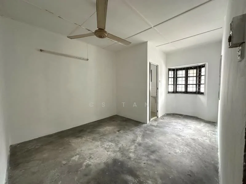 Room features: white painted walls, concrete flooring, ceiling fan, window with metal grille, door to adjacent room, suspended ceiling, light source from window.