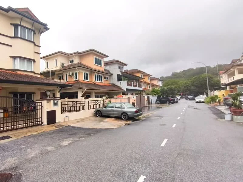 Exterior type: linked terrace house; features: two-storey houses, cream painted facade, red tiled roof, driveway with interlocking pavers, manicured lawn, surrounded by greenery, street view with parked cars, sidewalk, gated entrance; style: modern.