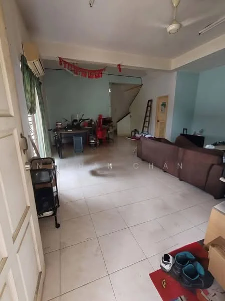 Living features: white painted walls, tile flooring, ceiling fan, sofa in brown, coffee table, window with green curtains, staircase in background, decorative items on shelves, shoes on the floor, open layout, natural light from window.