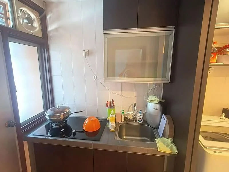 Kitchen features: black cabinetry, stainless-steel sink, chrome pull-down faucet, gas stove with wok burner, exhaust hood, countertop with dark surface, kitchen utensils on countertop, orange bowl, dish soap dispenser, built-in microwave, white tiled backsplash, window for natural light; style: modern.