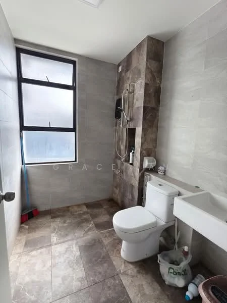 Bathroom features: grey tiled walls, light grey tiled flooring, walk-in shower with glass panel, chrome shower head, wall-mounted shower controls, white one-piece toilet, white sink with cabinet, window with black frame, cleaning supplies visible, broom in corner; style: modern.