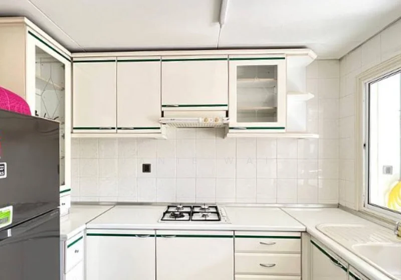 Kitchen features: white cabinetry with green trim, stainless-steel sink, chrome pull-down faucet, built-in gas hob, exhaust hood, white tiled backsplash, white countertop, glass-front upper cabinets, refrigerator, window with white frame; style: modern.